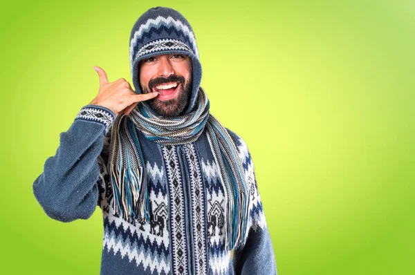Mannen med vinter kläder gör telefonen gest på färgglada backgro — Stockfoto