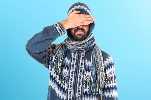 Человек в зимней одежде закрывает глаза на красочном фоне — стоковое фото