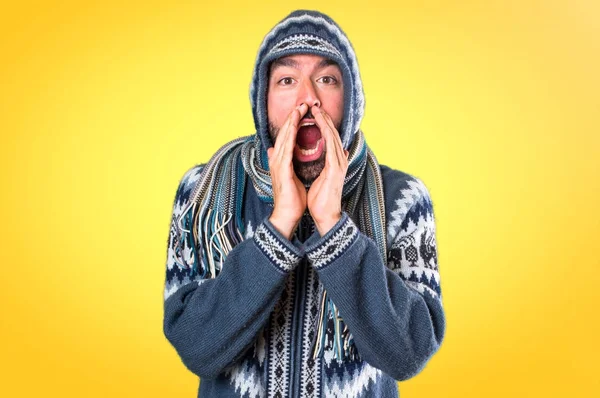 Чоловік з зимовим одягом кричить на барвистому фоні — стокове фото