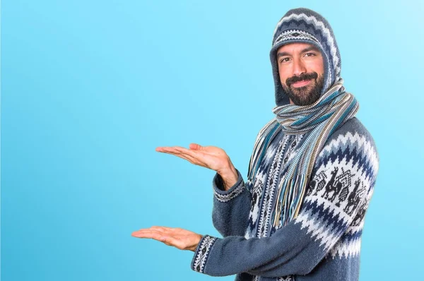 Mannen med vinterkläder presentera något på färgglada backgro — Stockfoto