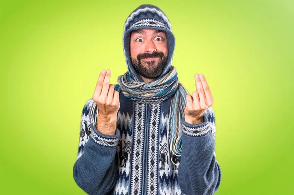Mannen med vinter kläder gör pengar gest på färgglada backgro — Stockfoto