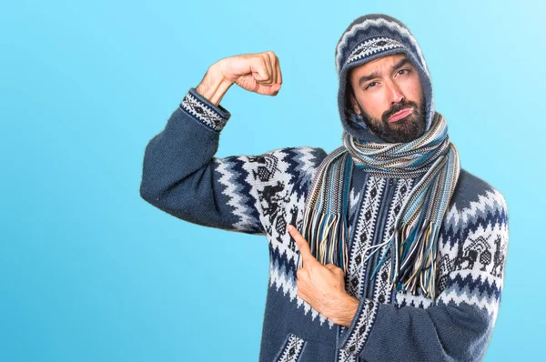 Hombre con ropa de invierno haciendo un gesto fuerte en backgr colorido —  Fotos de Stock