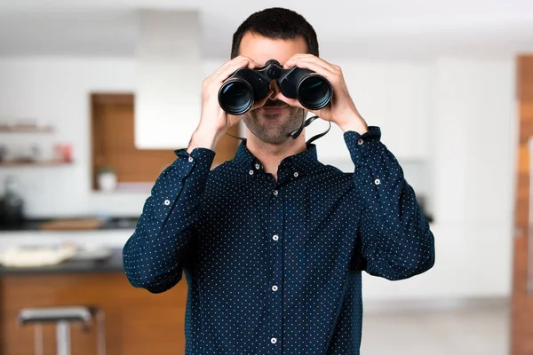 Hombre guapo con prismáticos dentro de casa — Foto de Stock