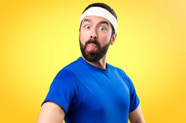 Funny sportsman taking out his tongue on colorful background — Stock Photo, Image