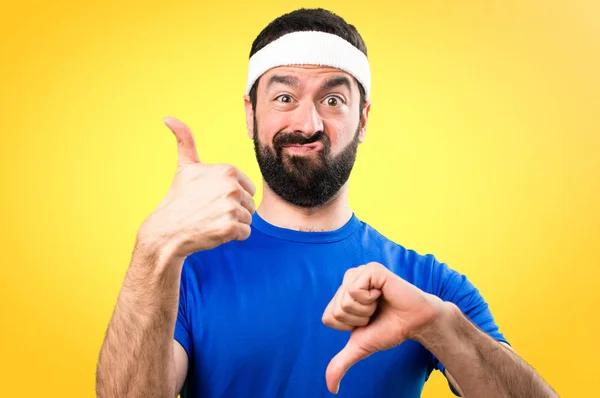 Funny sportsman making good-bad sign on colorful background — Stock Photo, Image