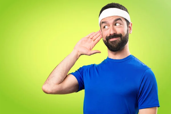 Funny sportsman listening something on colorful background — Stock Photo, Image