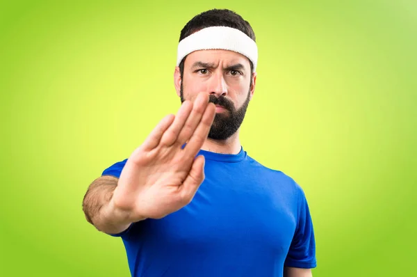 Funny sportsman making stop sign on colorful background — Stock Photo, Image