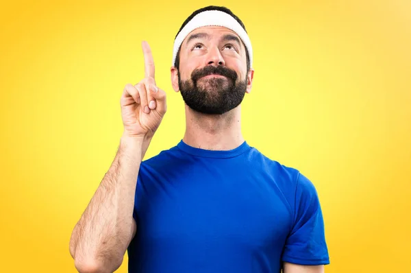 Αστεία αθλητή που δείχνει προς τα επάνω σε πολύχρωμο φόντο — Φωτογραφία Αρχείου