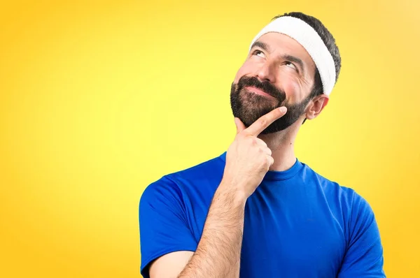 Funny sportsman thinking on colorful background — Stock Photo, Image