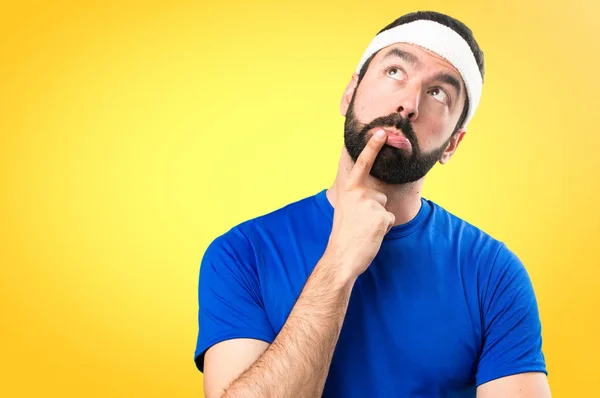 Funny sportsman having doubts on colorful background — Stock Photo, Image