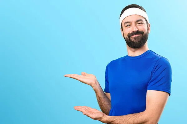 Funny sportsman presenting something on colorful background — Stock Photo, Image