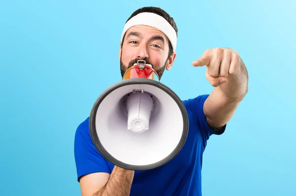 Αστεία αθλητή κρατώντας ένα μεγάφωνο σε πολύχρωμο φόντο — Φωτογραφία Αρχείου