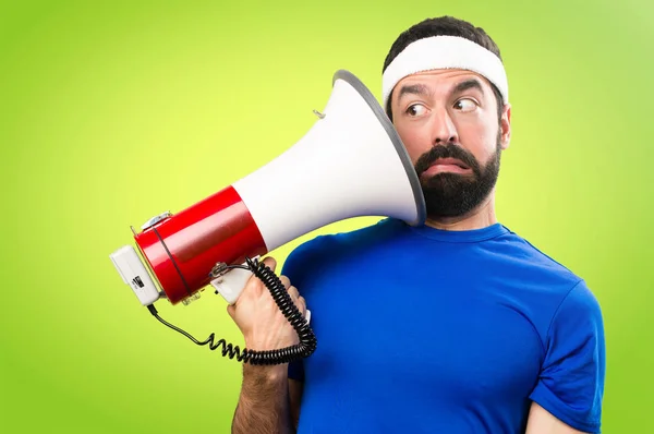 Grappige sportman houden een megafoon op kleurrijke achtergrond — Stockfoto