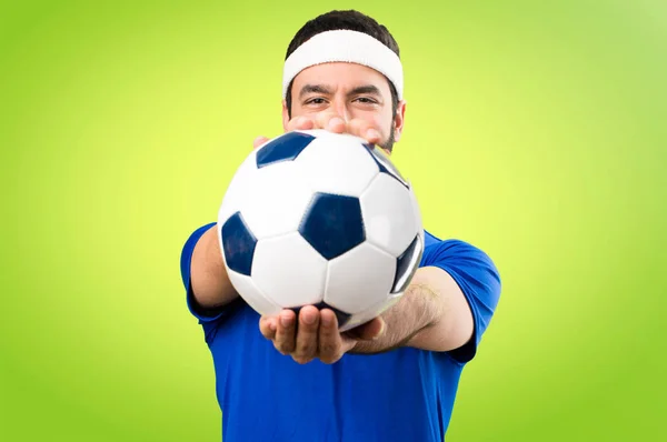 Grappige sportman houden een voetbal op kleurrijke achtergrond — Stockfoto
