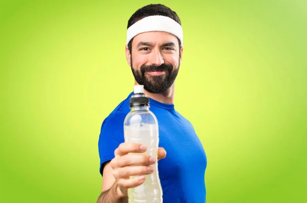 快乐滑稽的运动员与一瓶水在五颜六色的 backgro — 图库照片