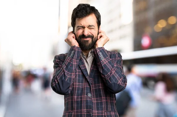 Goed geklede man die betrekking hebben op zijn oren in de stad — Stockfoto