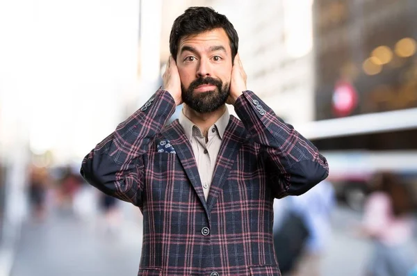 Goed geklede man die betrekking hebben op zijn oren in de stad — Stockfoto