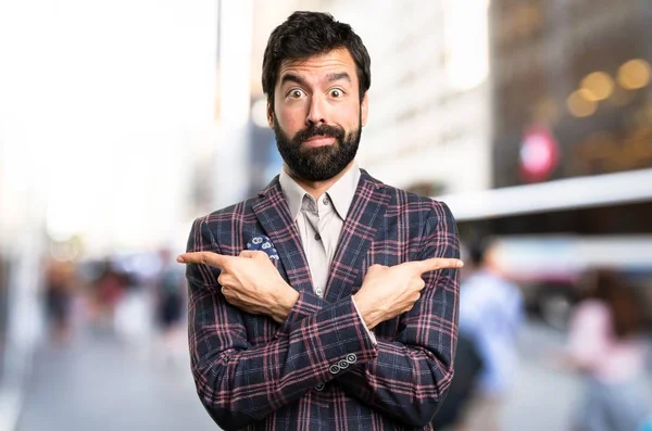 Dobře oblečený muž ukazující na přípojky s pochybnosti ve městě — Stock fotografie