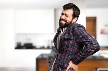 İyi giyimli adam evin içinde sırt ağrısı ile