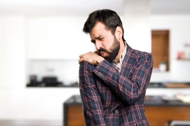 İyi giyimli adam evin içinde omuz ağrısı ile