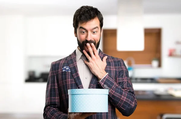 Välklädd man innehar en gåva inuti huset — Stockfoto