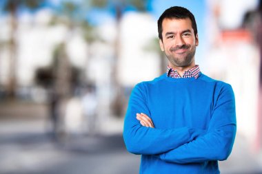 Yakışıklı genç adam kollarını ile odaklanmamış arka plan üzerinde çarpı işareti