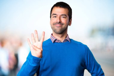 Yakışıklı genç odaklanmamış arka plan üzerinde sayım dört adam