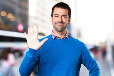 Yakışıklı genç odaklanmamış arka plan üzerinde sayım beş adam