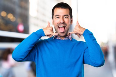 Yakışıklı genç yapım telefon jest odaklanmamış arka plan üzerinde