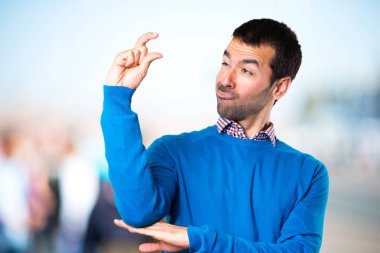 Yakışıklı genç adam küçük işareti odaklanmamış arka plan yapma