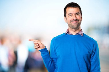 Lateral odaklanmamış backgrou üzerinde işaret eden yakışıklı genç