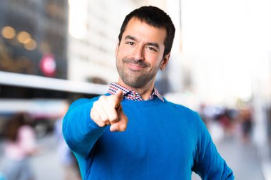 Odaklanmamış arka plan üzerine açık işaret eden yakışıklı genç