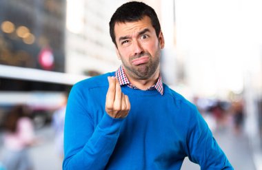 Yakışıklı genç yapım para jest odaklanmamış arka plan üzerinde