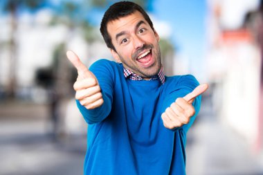 Yakışıklı delikanlı odaklanmamış arka plan üzerinde başparmak ile