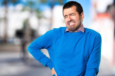Yakışıklı delikanlı odaklanmamış arka plan üzerinde sırt ağrısı ile