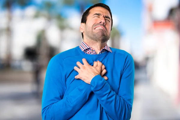 Hombre joven guapo con dolor de corazón en un fondo desenfocado —  Fotos de Stock