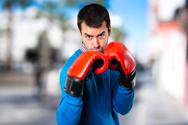 Bello giovanotto con i guanti da boxe su sfondo sfocato — Foto Stock