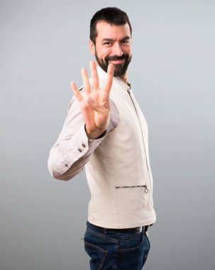 Yakışıklı erkek yelek gri arka plan üzerine dört sayma ile