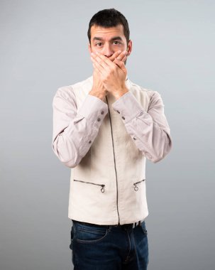 Yakışıklı adam ağzını gri arka plan üzerinde kapsayan yelek ile