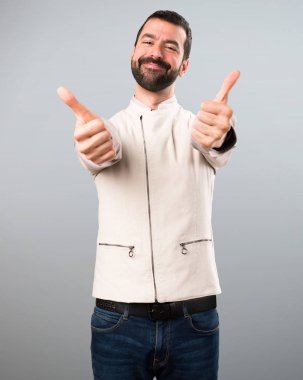 Yelek gri arka plan üzerinde başparmak ile yakışıklı adam