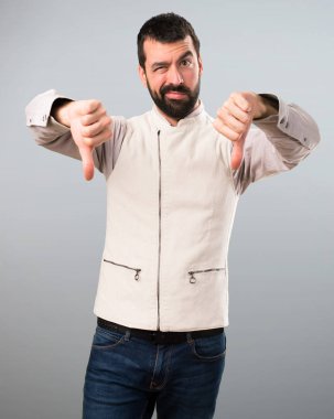 Yelek gri arka plan üzerinde kötü sinyal verme ile yakışıklı adam