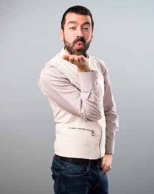 Yelek gri arka plan üzerinde bir öpücük gönderme ile yakışıklı adam