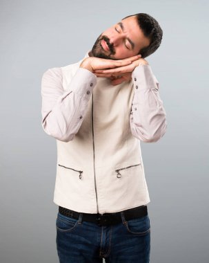 Yelek yapımı uyku jest gri arka plan üzerinde olan yakışıklı adam