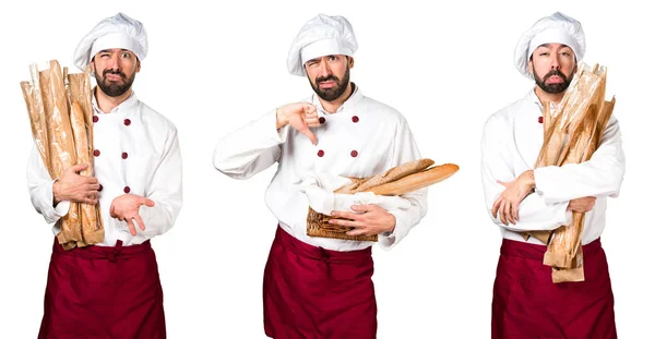 Young baker holding some bread and making bad signal — Stock Photo, Image