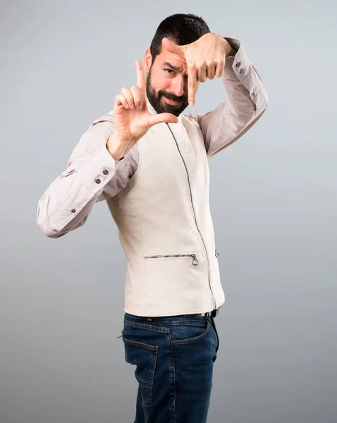 Bello uomo con gilet concentrandosi con le dita sul retro grigio — Foto Stock