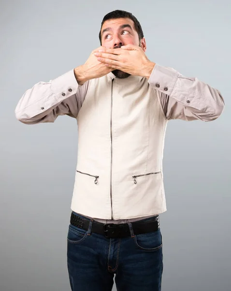 Knappe man met vest maken verrassing gebaar op grijze pagina — Stockfoto