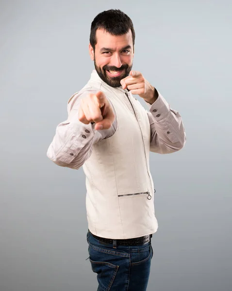 Hombre guapo con chaleco apuntando al frente sobre fondo gris —  Fotos de Stock