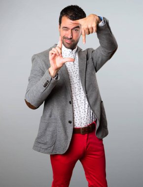 Yakışıklı adam onun parmaklarıyla gri arka plan üzerinde duruluyor