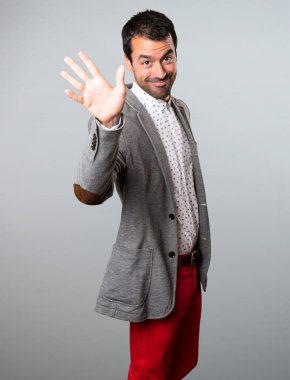 Yakışıklı adam gri arka plan üzerinde selamlayan