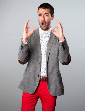 Yakışıklı adam gri arka plan üzerinde oturum Tamam yapma